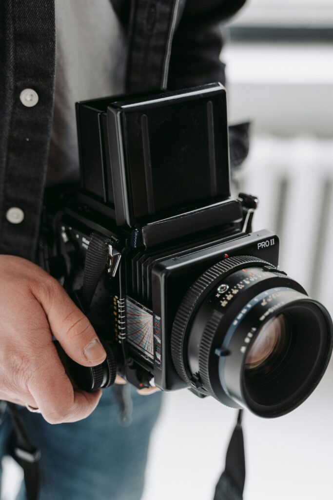 A man holding a vintage medium format camera, showcasing classic photography equipment.