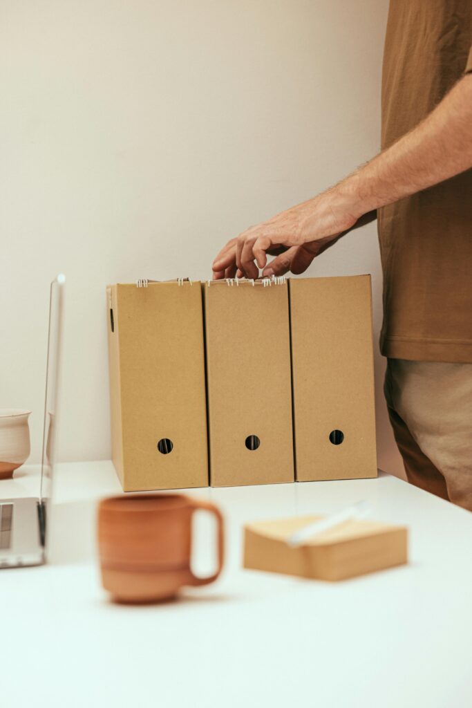 A person organizing files at a minimalist home office desk with a cup of coffee.